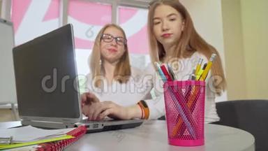两个十几岁的女生一起学习，使用笔记本电脑